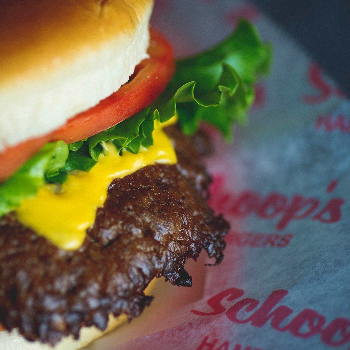 A hamburger is sitting on a piece of paper that says ' schoo 's ' on it