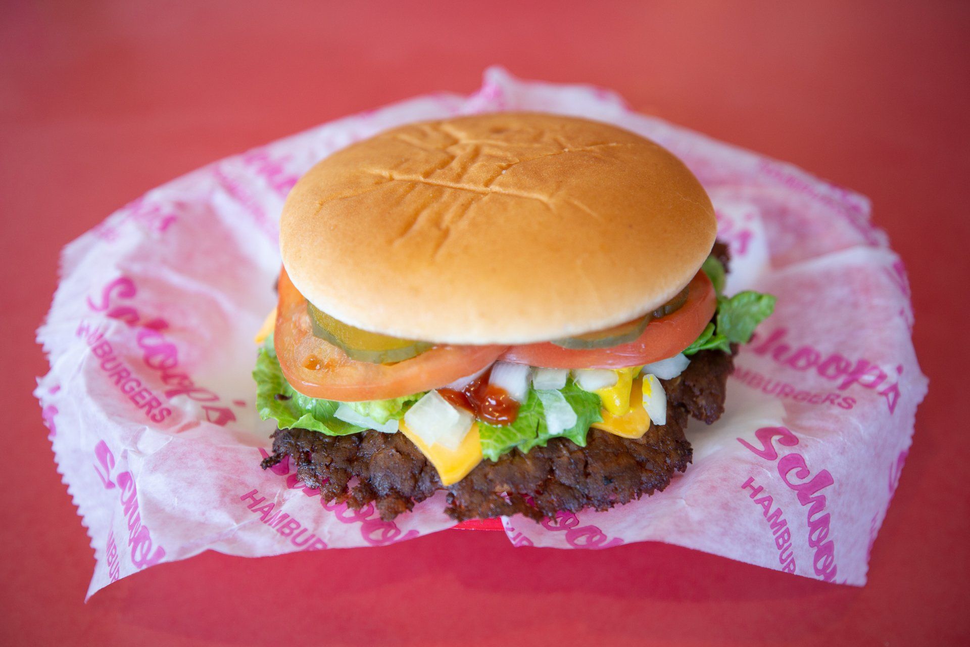 A hamburger is sitting on a piece of paper on a table.