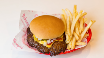 A hamburger and french fries in a red basket on a table.