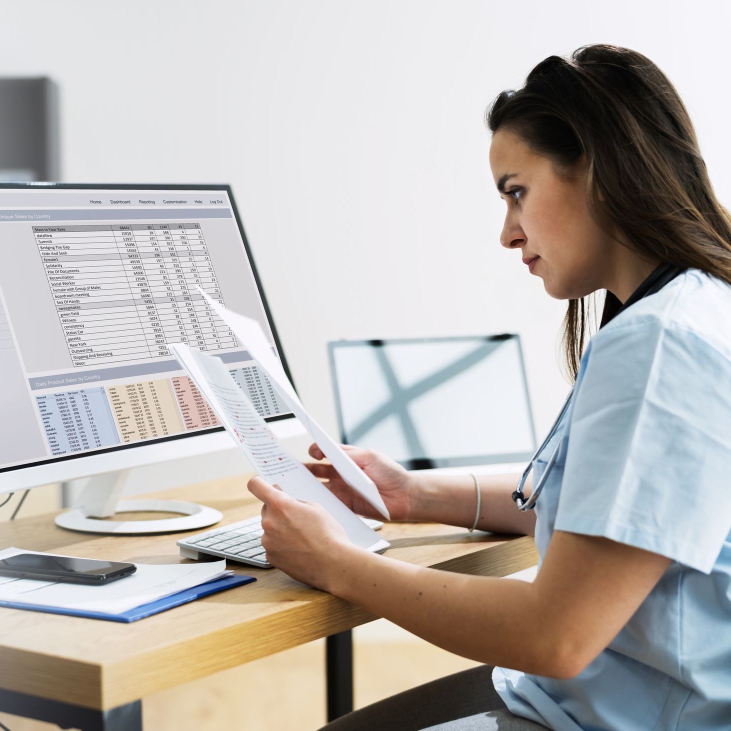 A nurse is sitting at a desk looking at a computer screen.