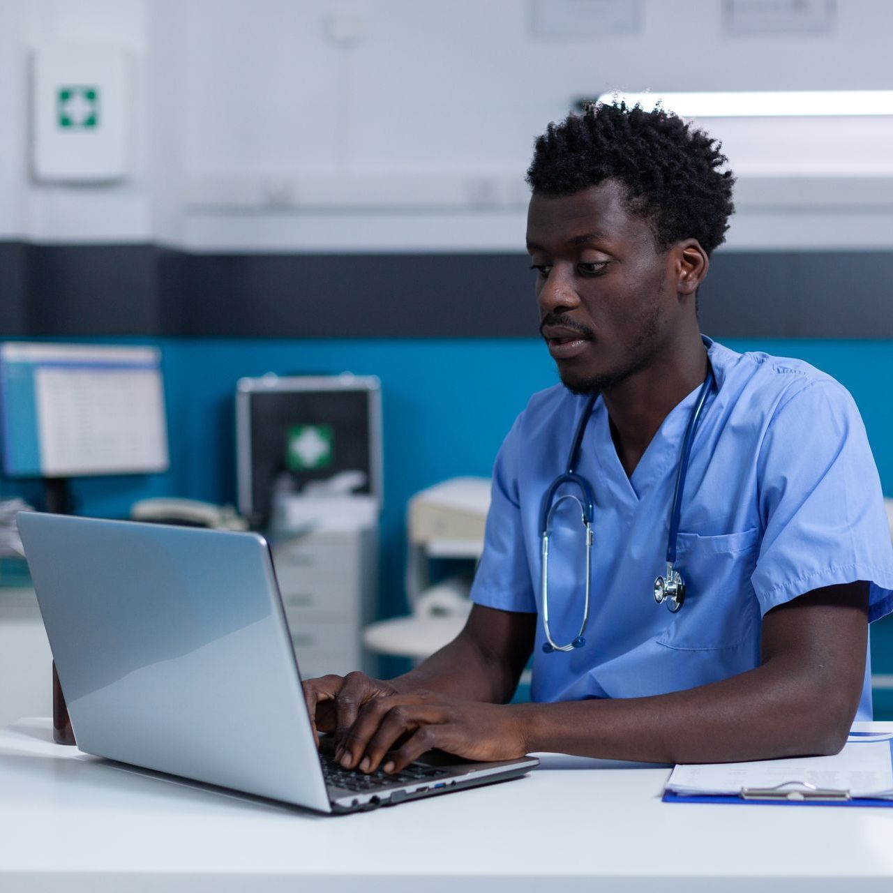 A doctor is sitting at a desk using a laptop computer.