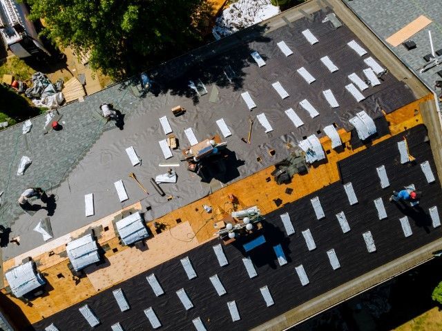 Aerial view of pedestrians and white vehicles on a road with orange and black lane markings.