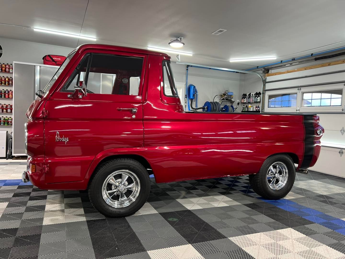 A red truck is parked in a garage with a checkered floor.