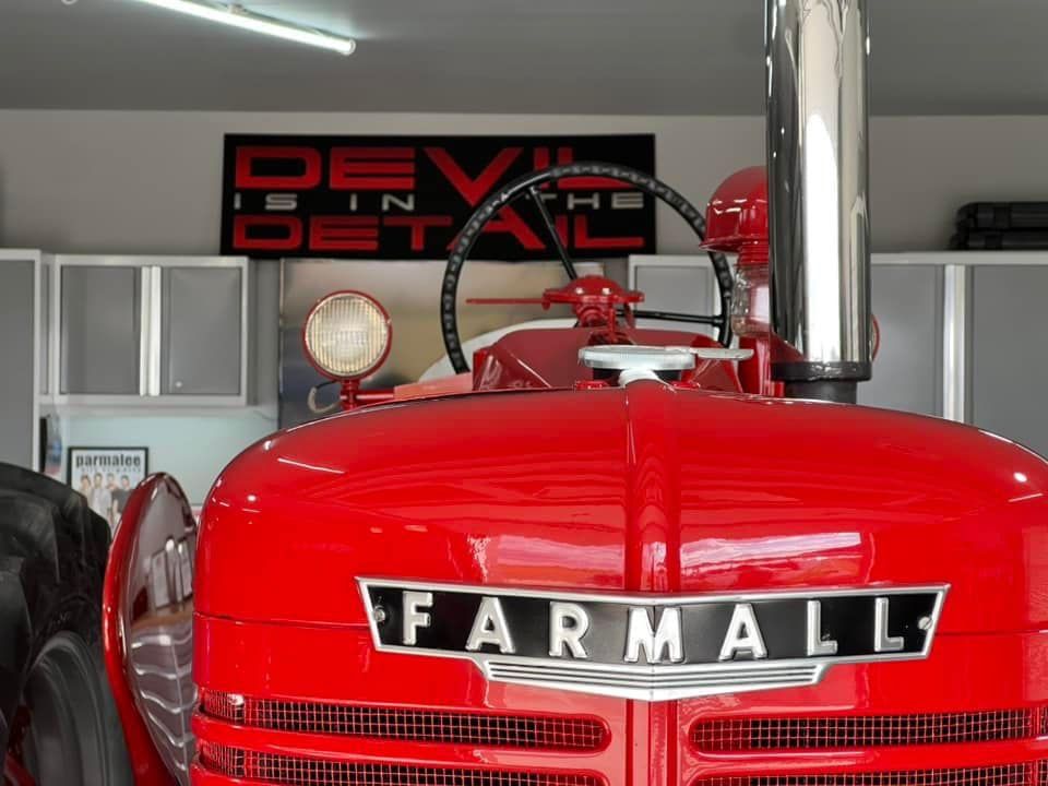 A red farmall tractor is parked in a garage