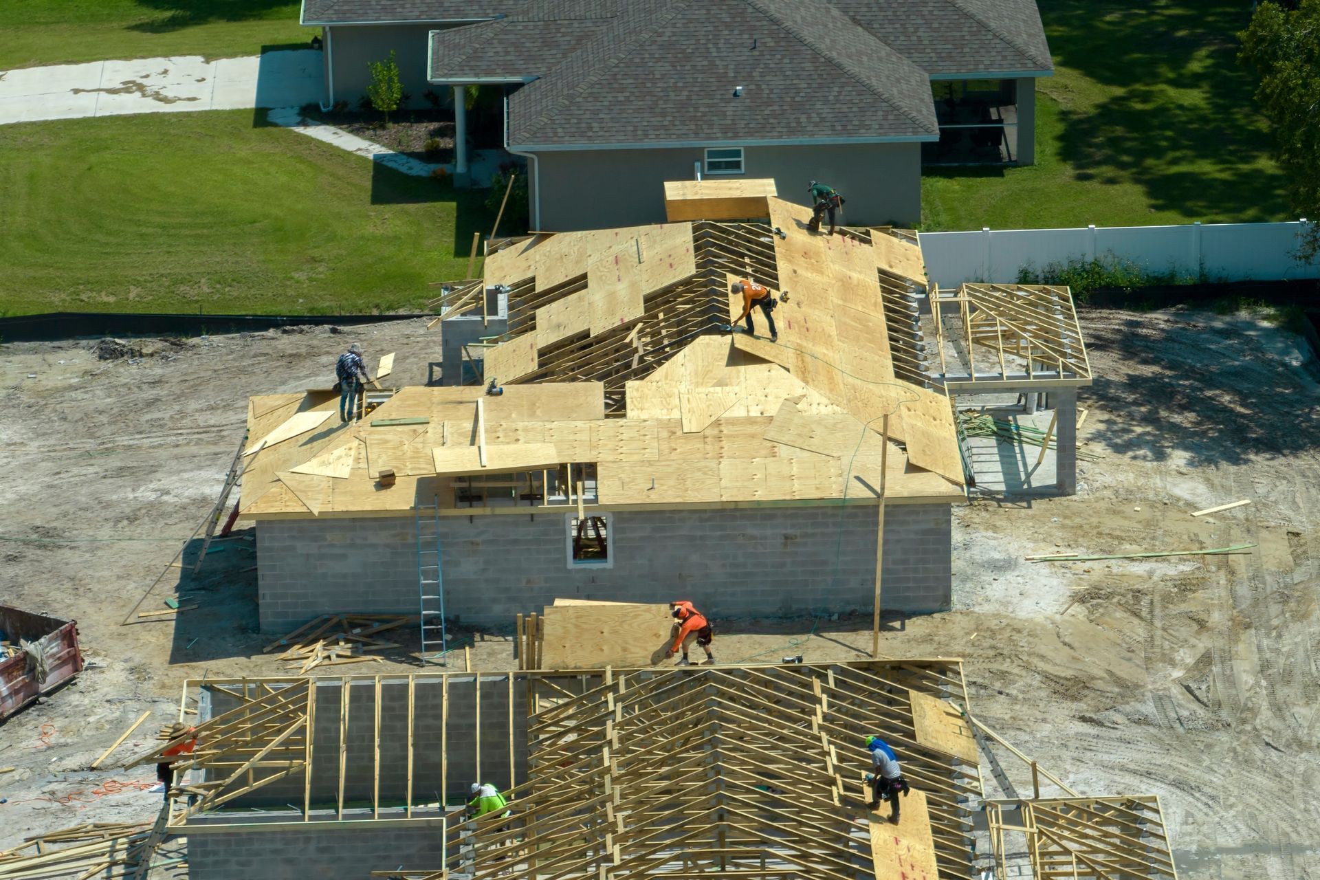 An aerial view of a house under construction with workers on the roof