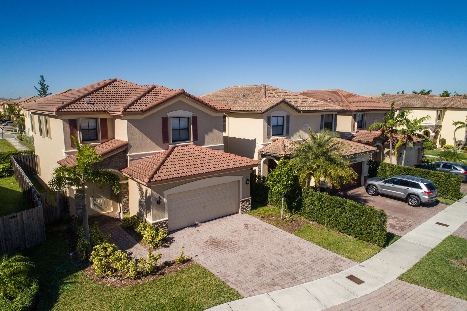 An aerial view of a house in a residential area with cars parked in front of it.