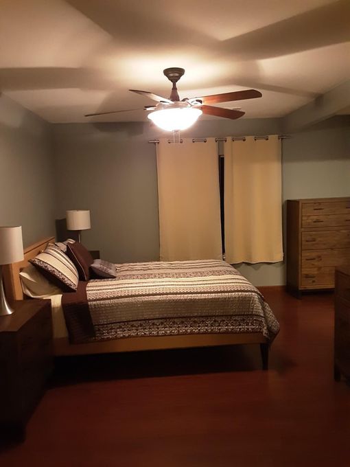 A bedroom with a bed and a ceiling fan