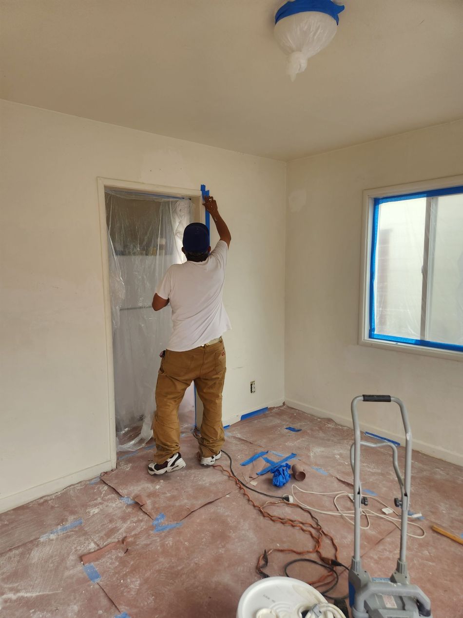 A man is standing in a room painting a wall.