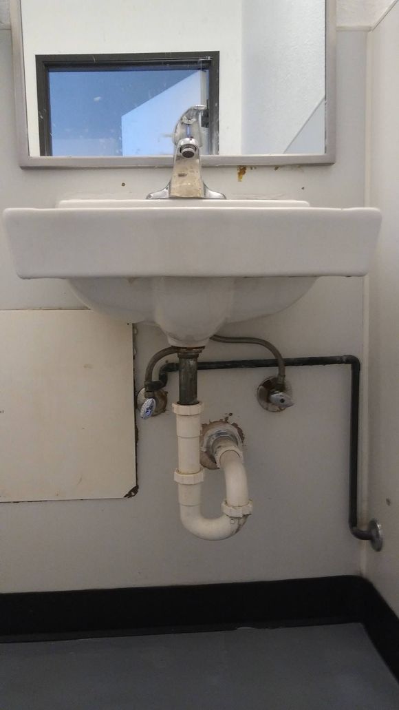 A bathroom sink with a pipe underneath it and a mirror.