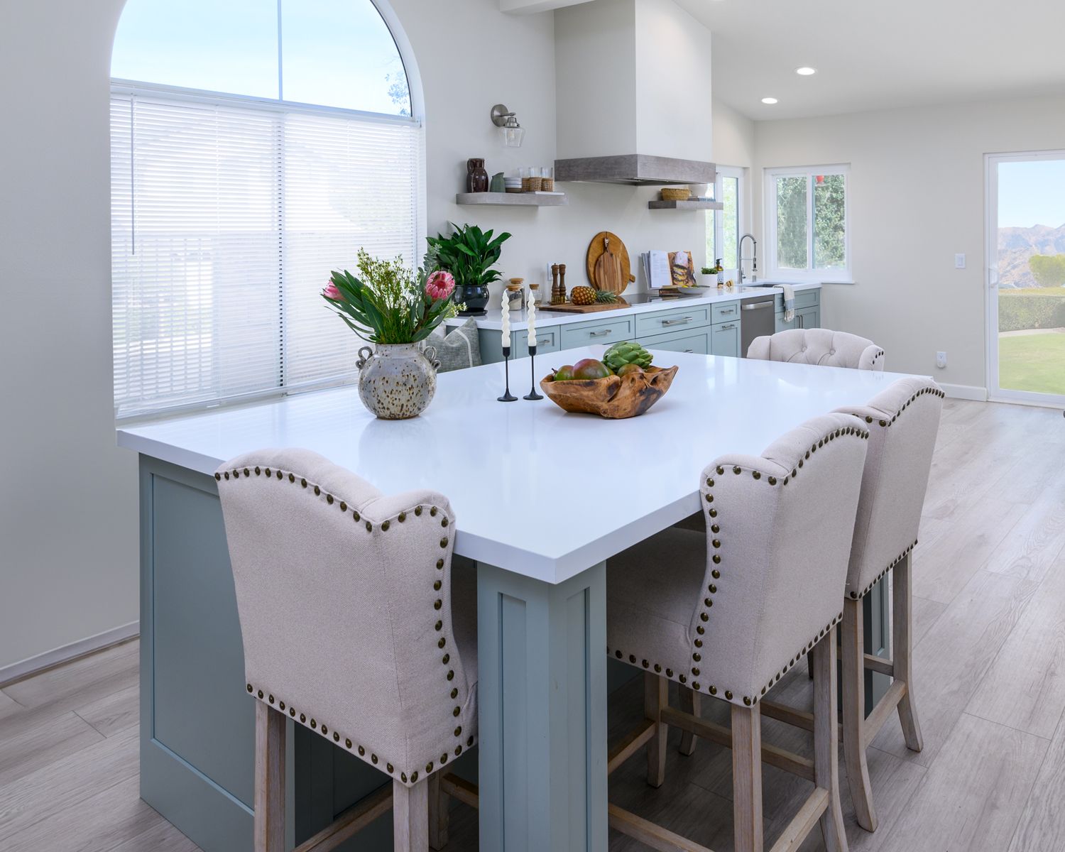 kitchen island with 4 chairs n the foreground and kitchen cabinets on the back wall, mint painted cabinets, light green cabinets, white quartz countertops, range hood blower, luxury vinyl flooring, Rancho Conejo Neighborhood, Newbury Park, CA kitchen remodel