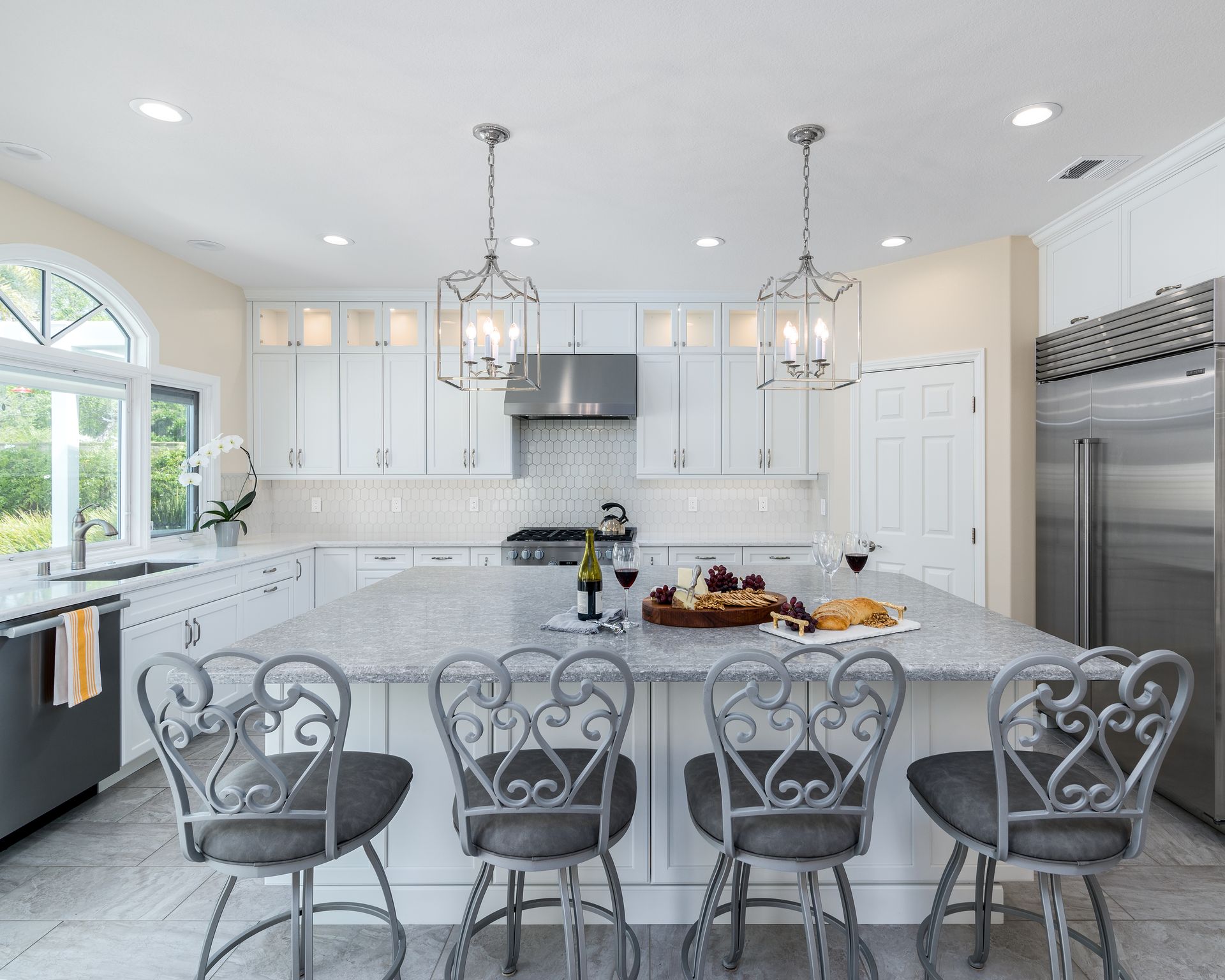 image shows a large kitchen with white painted frameless DuraSupreme Cabinets, large island and 4 barstools in the foreground, Newbury Park, CA, Open Concept Kitchen Expansion and Remodel