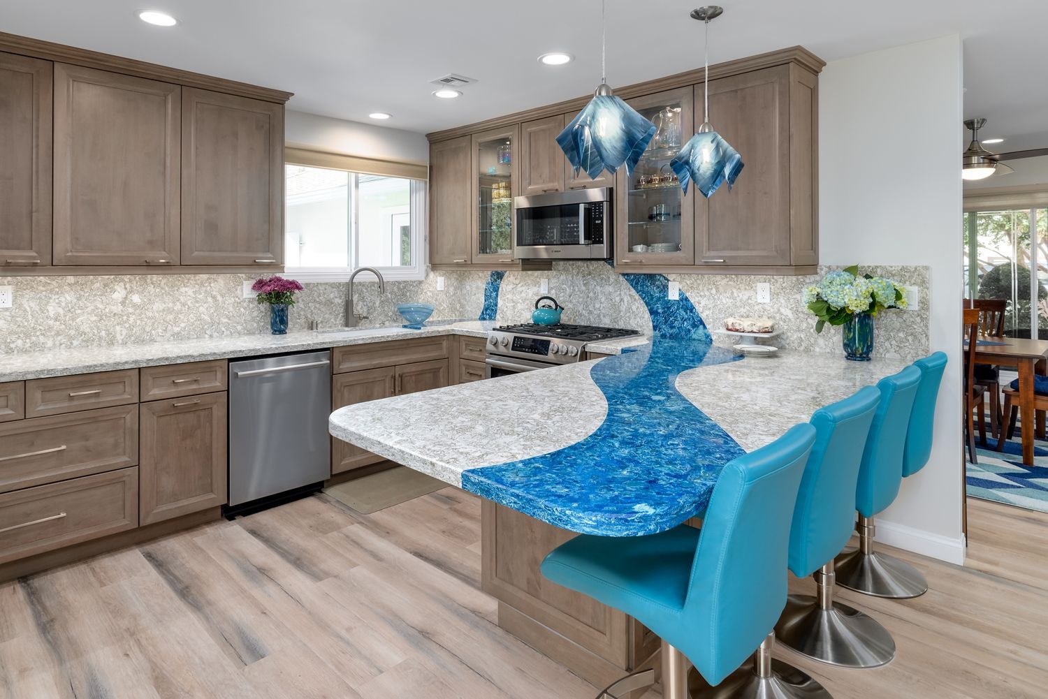 image shows a kitchen with a blue and white quartz counter, light wood cabinets and light wood floors, West Hills, CA home remodel 