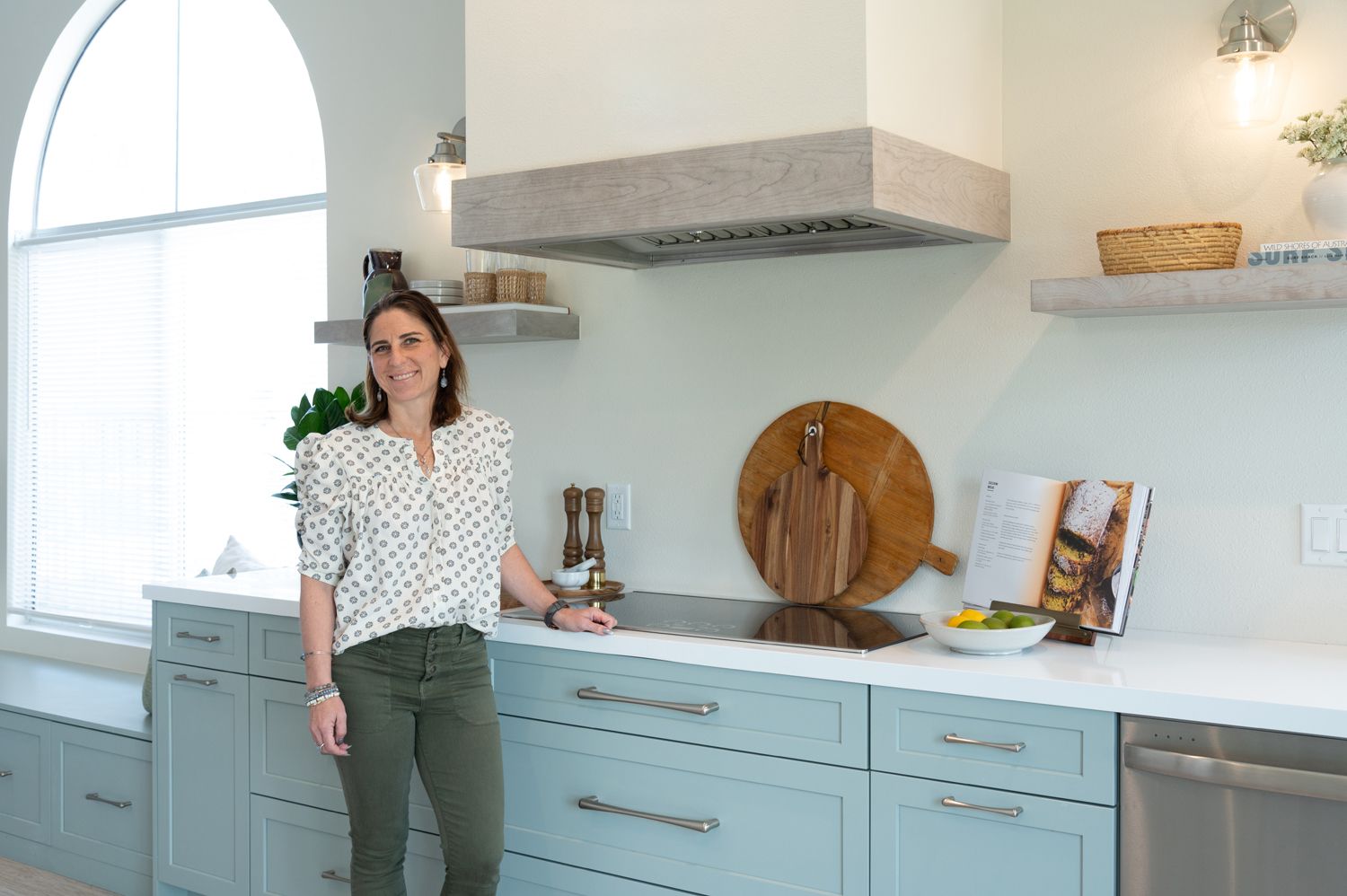 image of Westside Remodeling's kitchen and bath designer in a recently completed Newbury Park, CA kitchen remodel, mint painted cabinets, light green cabinetry, white quartz countertops, range hood blower, induction cooktop, floating shelves, Rancho Conejo Neighborhood, Newbury Park, CA open and airy kitchen remodel 