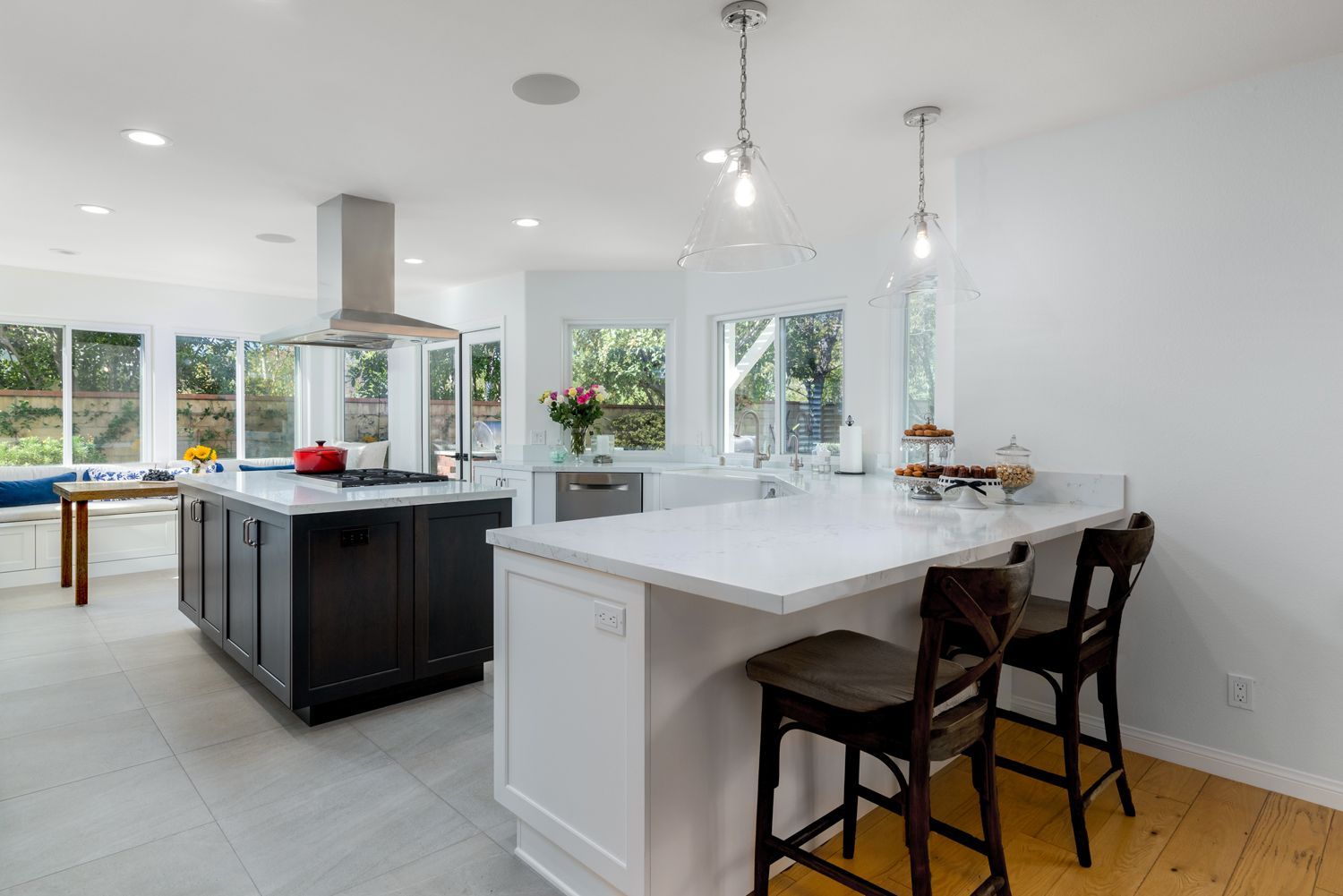 image of a kitchen with a peninsula  and two bar stools in the foreground and a small dark brown island and stainless steel hood in the background, Oak Park, CA Kitchen Remodel 