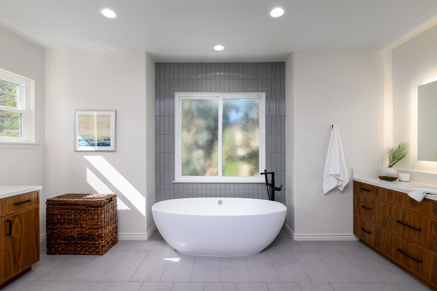 image shows a bathroom with a free standing bathtub in front of a gray tiled accent wall with a window in the center, primary bathroom remodel, Thousand Oaks, CA 