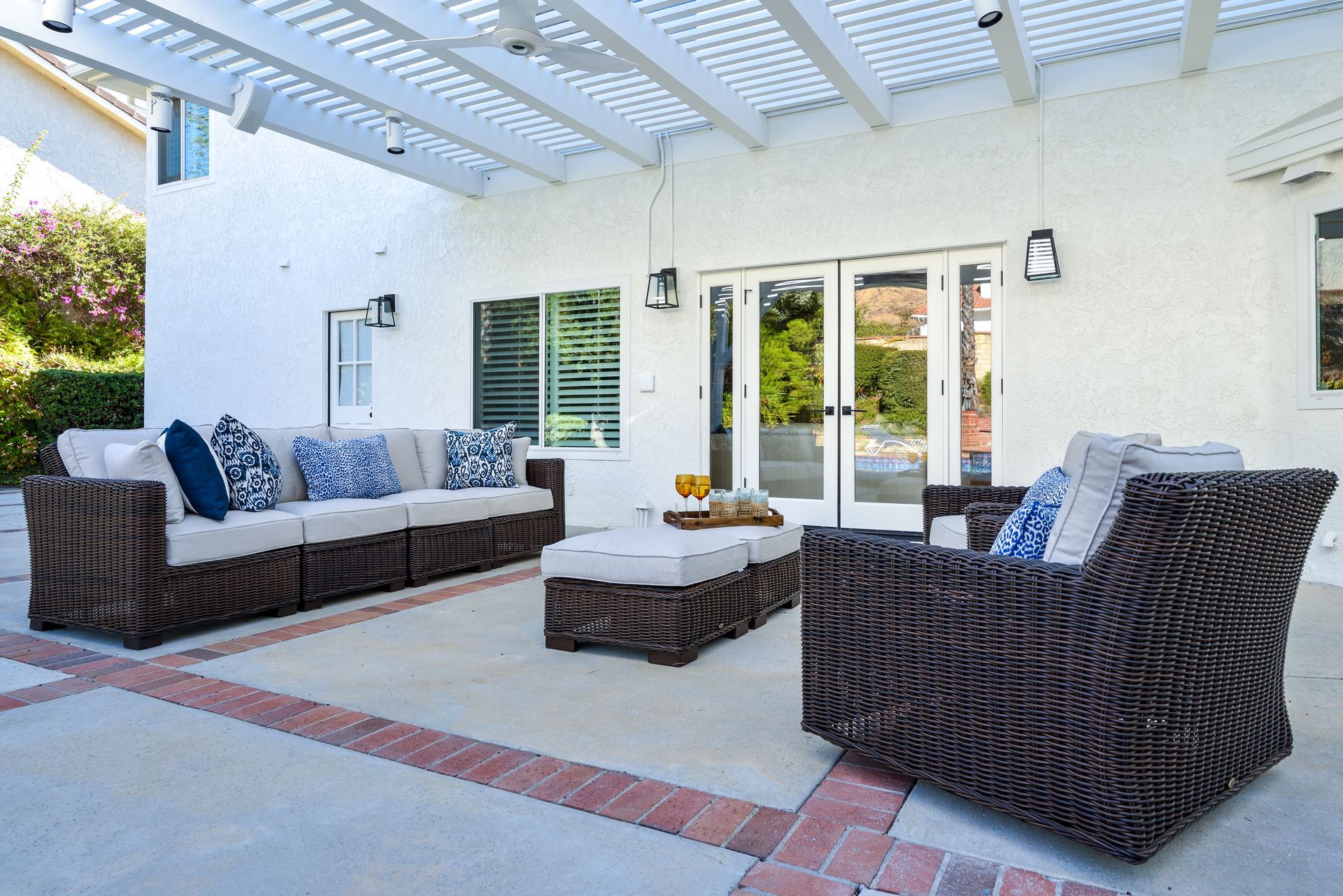 image shows a back patio with two wicker couches and a table and a white patio cover & fan over head, Oak Park, CA  back patio remodel 