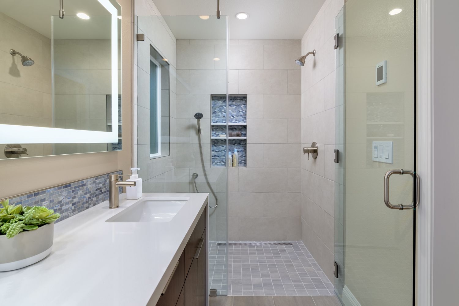 Image of a shower with beige tile and blue shampoo niche, white countertop on a dark wood vanity, lighted mirror, Home Addition Project, 2 bedrooms, 1 bathroom  , Thousand Oaks, CA 