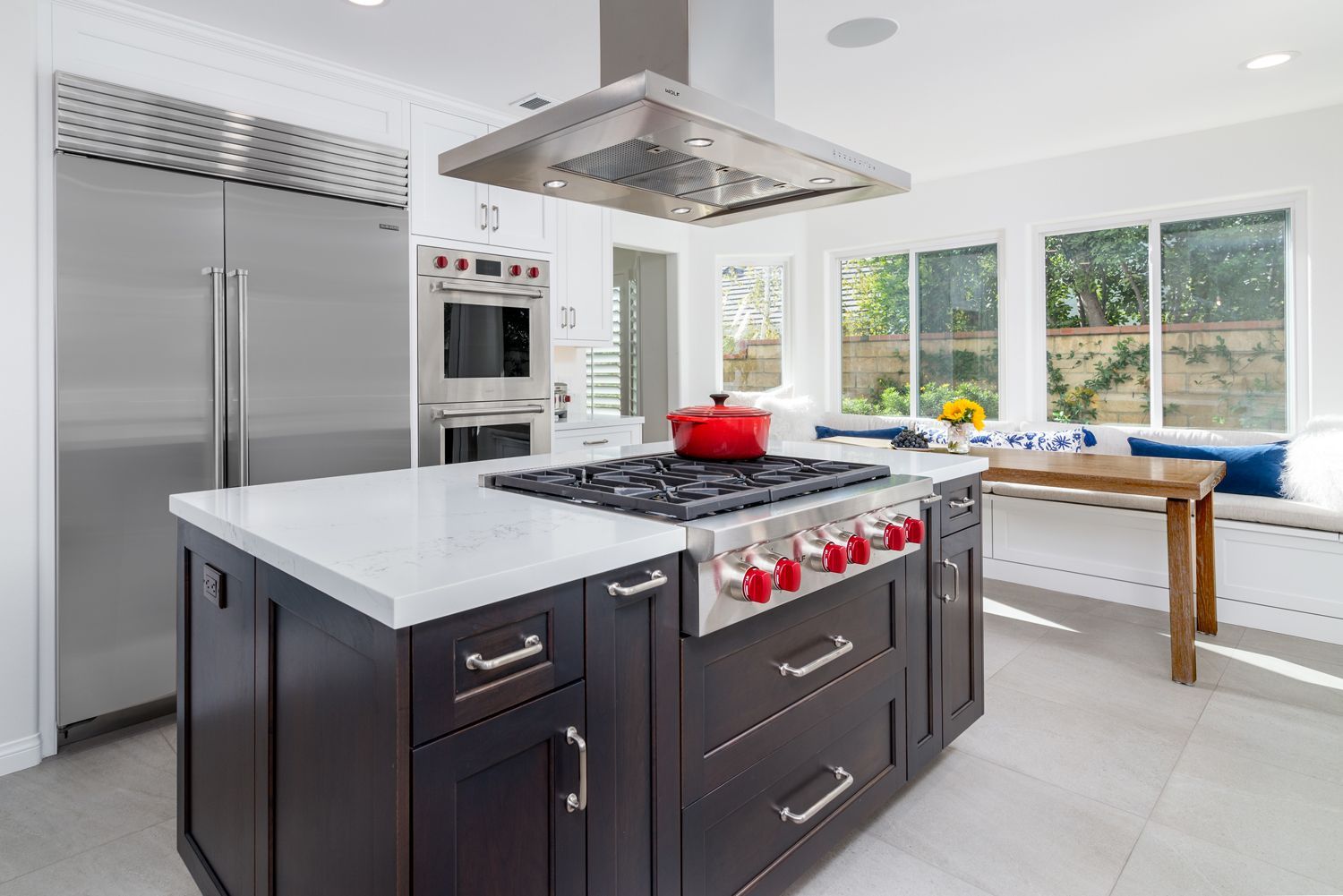 image of a kitchen with a dark brown island, white counter, cooktop with red control knobs, stainless steel appliances, Oak Park, CA Kitchen Remodel 