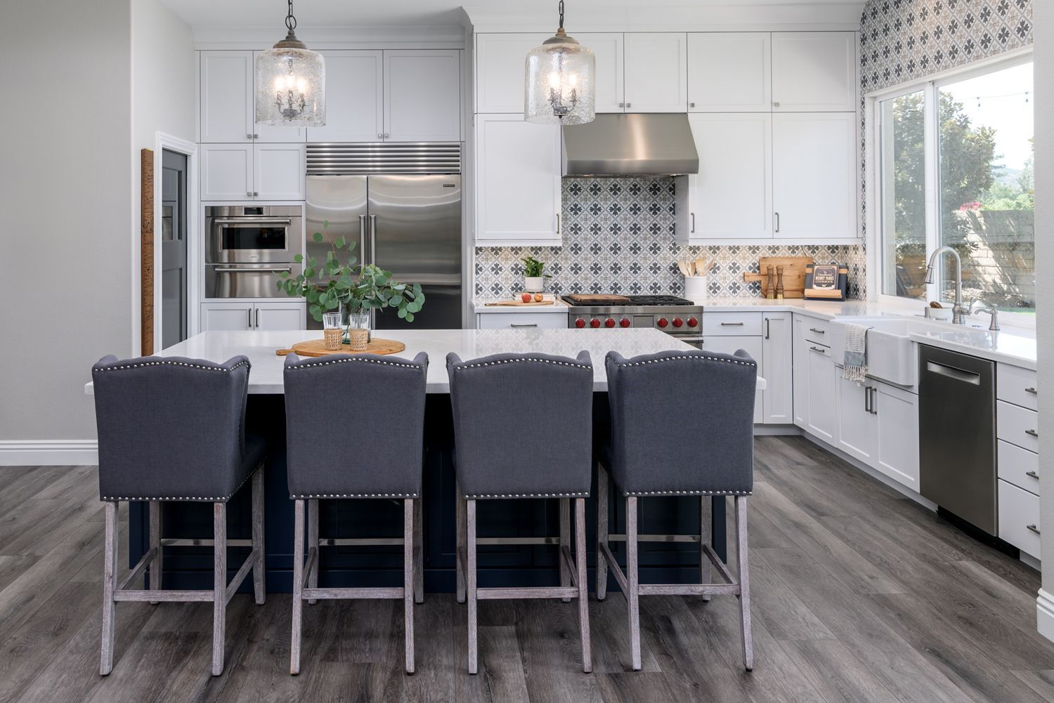 image shows a kitchen with white cabinets, a large island with 4 gray chairs and Fiore Martia accent tile , New Luxury Vinyl Flooring in Shades of Gray, Newbury Park, CA Kitchen Remodel 