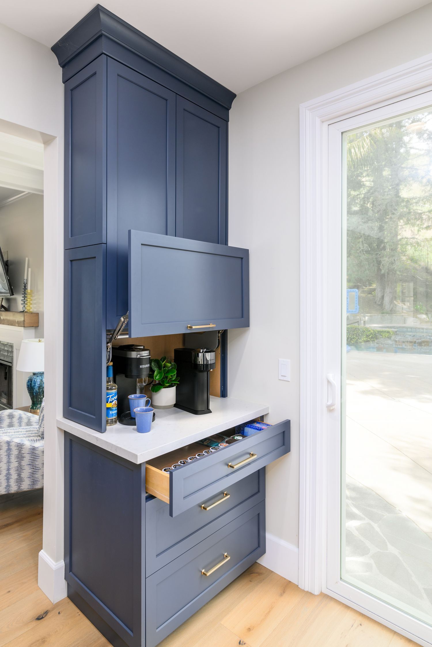image a tall navy blue cabinetry unit with an cabinet lifted up and a cabinet drawer pulled open, coffee bar cabinetry, Omega Full Access cabinetry, white quartz countertops, hardwood floors in French Oak,  Milgard sliding back door, Agoura Hills, modern style Kitchen Remodel