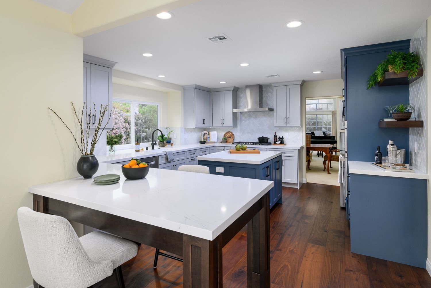 image of a kitchen with a counter height table with a white quartz countertop and dark wood base in the foreground, dark wood floors, Camarillo, CA kitchen remodel
