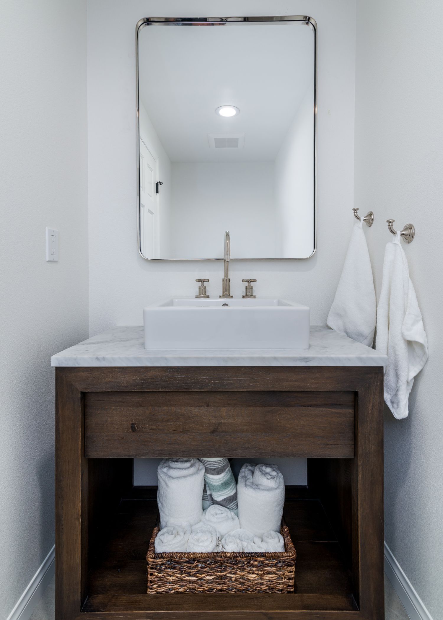 image shows a vanity in dark wood and a white countertop with a rectangular mirror above, Powder Bathroom Remode, Oak Park, CA 