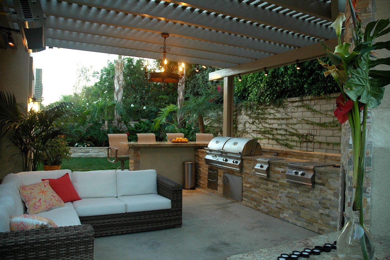 A patio with a couch and a grill under a pergola