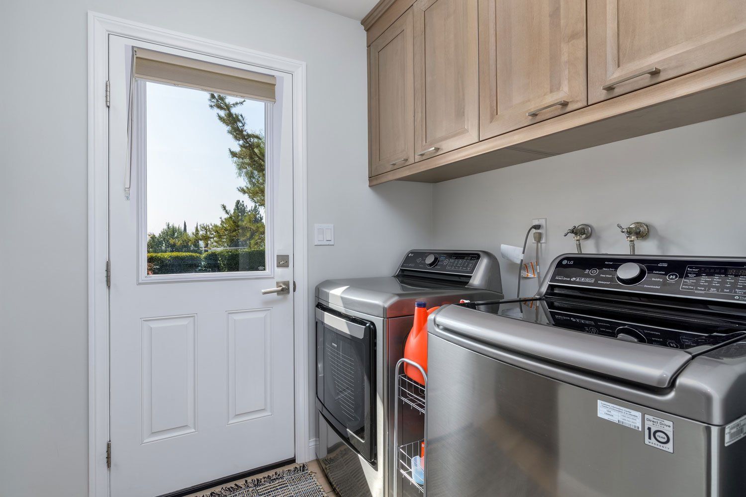 image shows a laundry room with a washer, dryer and light wood cabinets overhead, West Hills, CA Home Remodel 