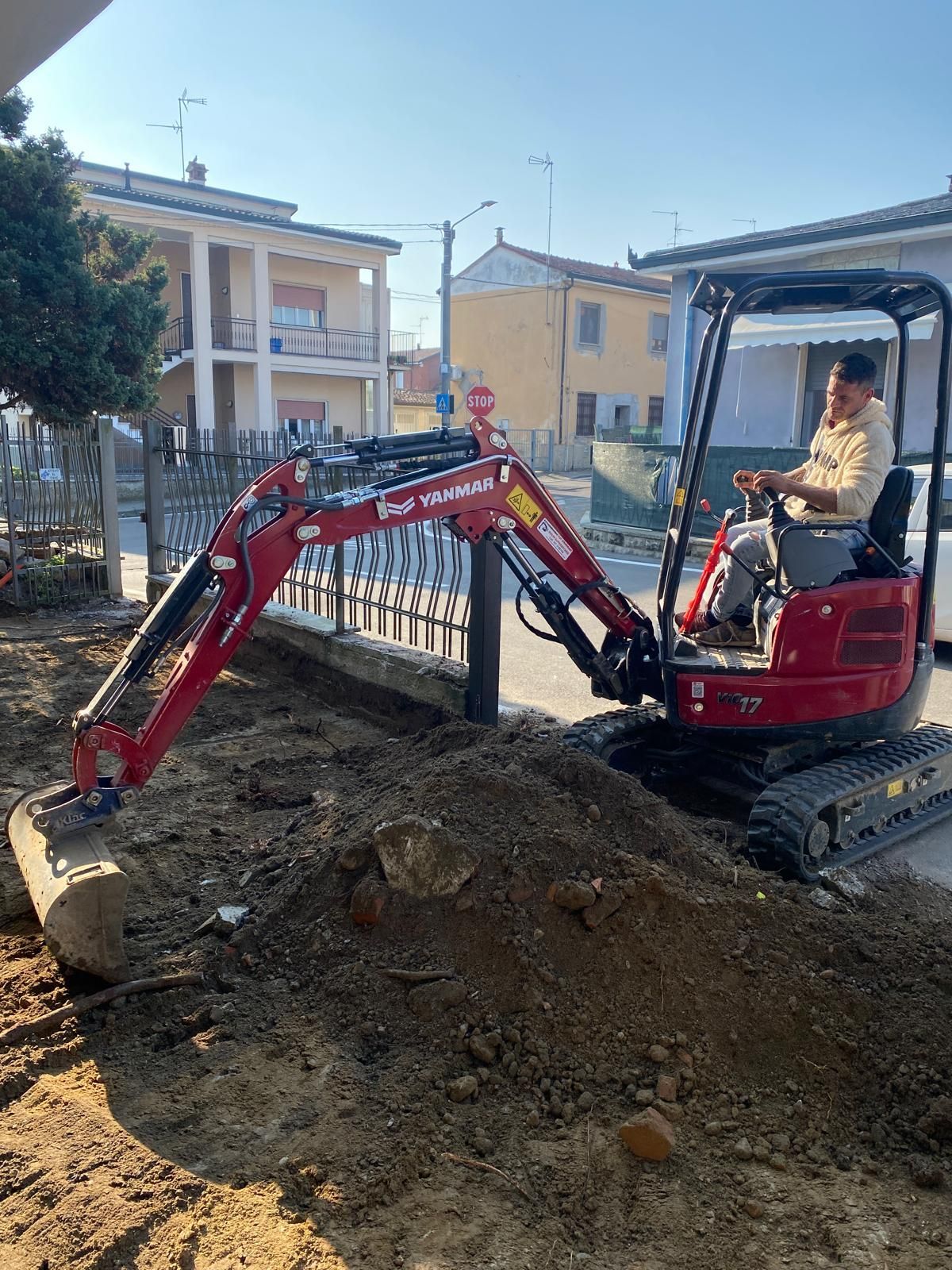 Un uomo sta guidando un piccolo escavatore su una strada sterrata.