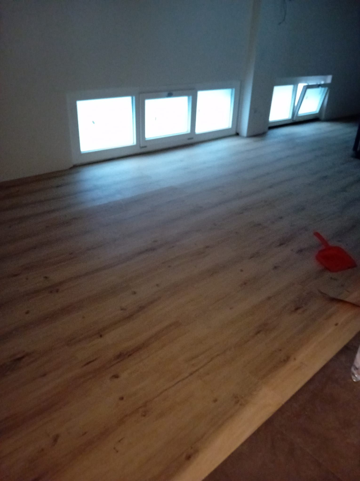 Una stanza con pavimento in legno e molte finestre