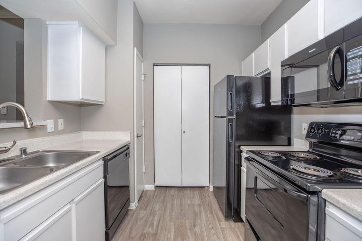 Kitchen with white cabinets, black appliances, gray walls, and wood-look flooring.