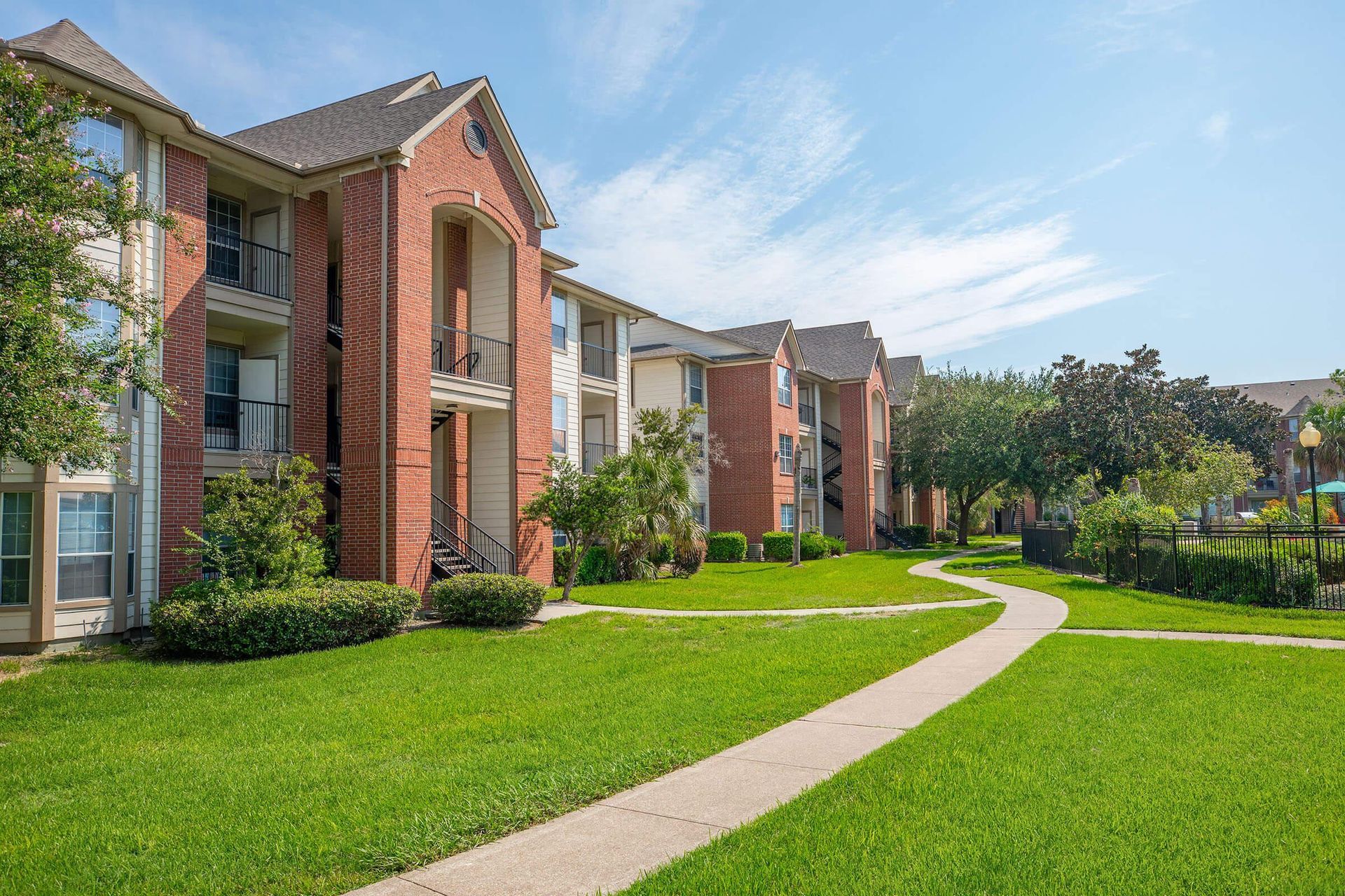 A brick apartment building with a lush green lawn in front of it at Windsor Estates.