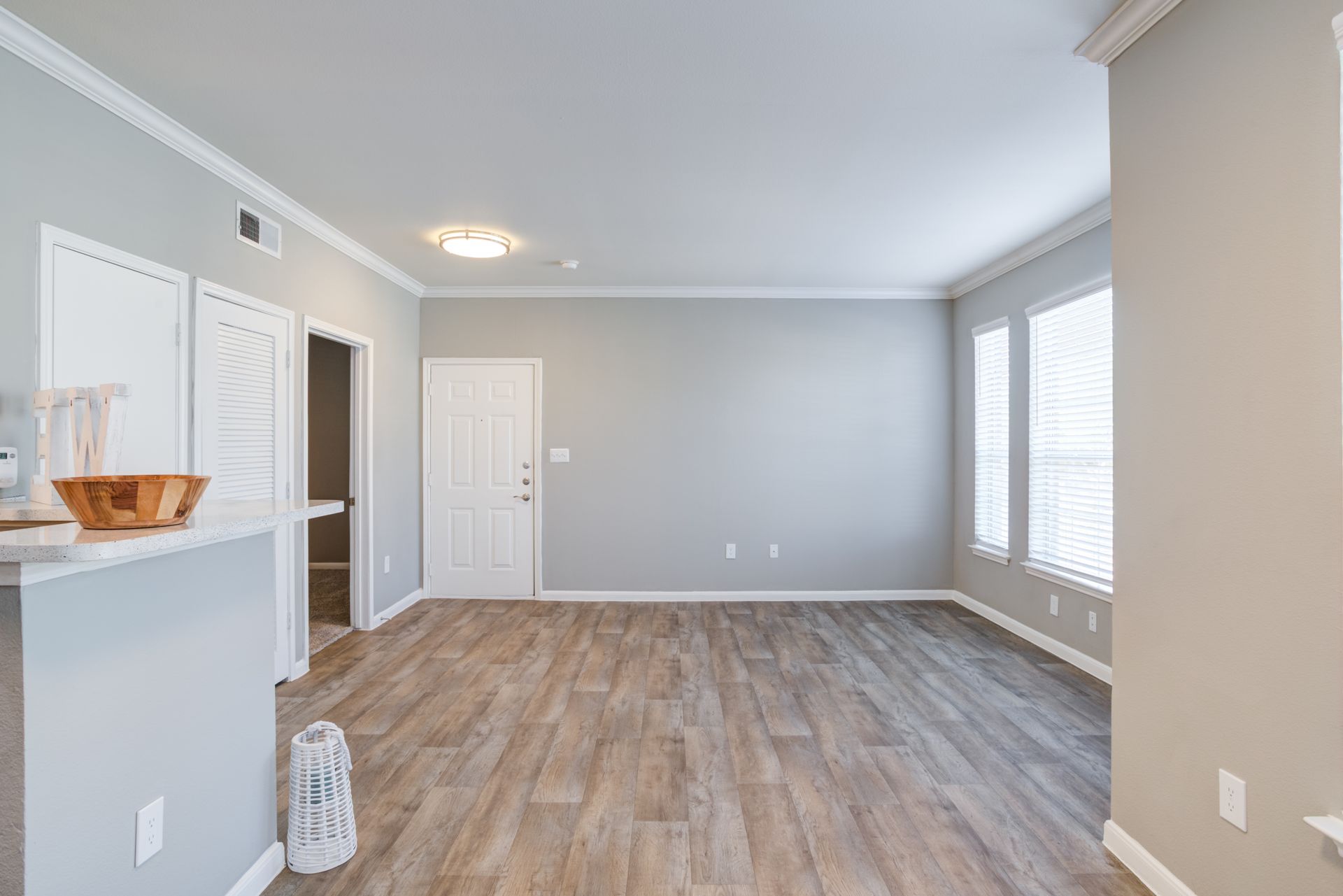 Kitchen with white cabinets, black appliances, gray walls, and wood-look flooring.