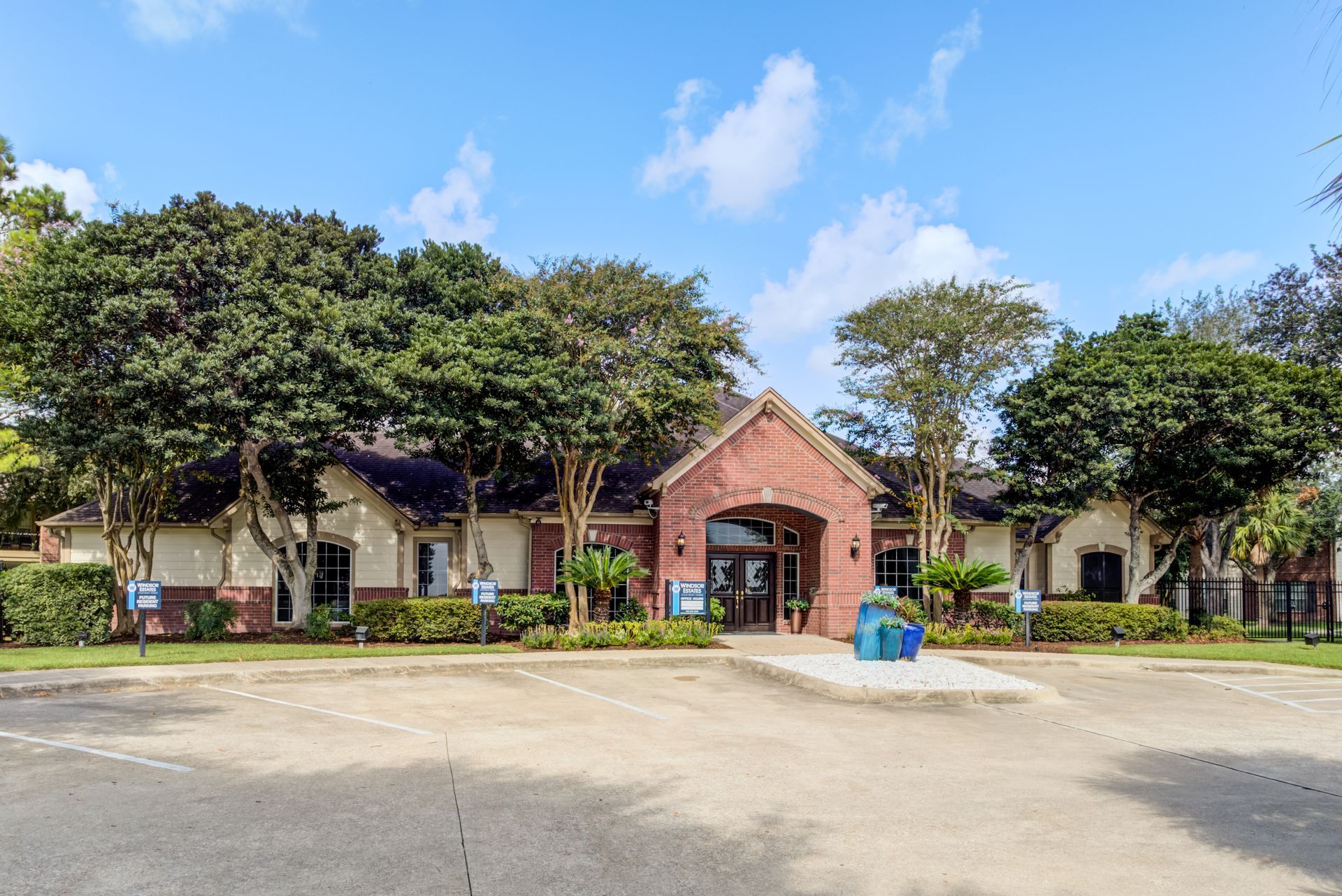 Outdoor seating area: pink cushions, yellow shade, gray furniture, surrounded by greenery.