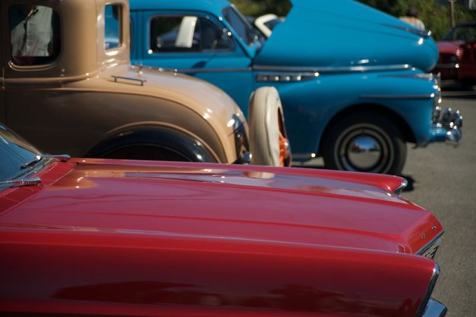 Auto d'epoca rosse, beige e blu allineate in una mostra automobilistica all'aperto.