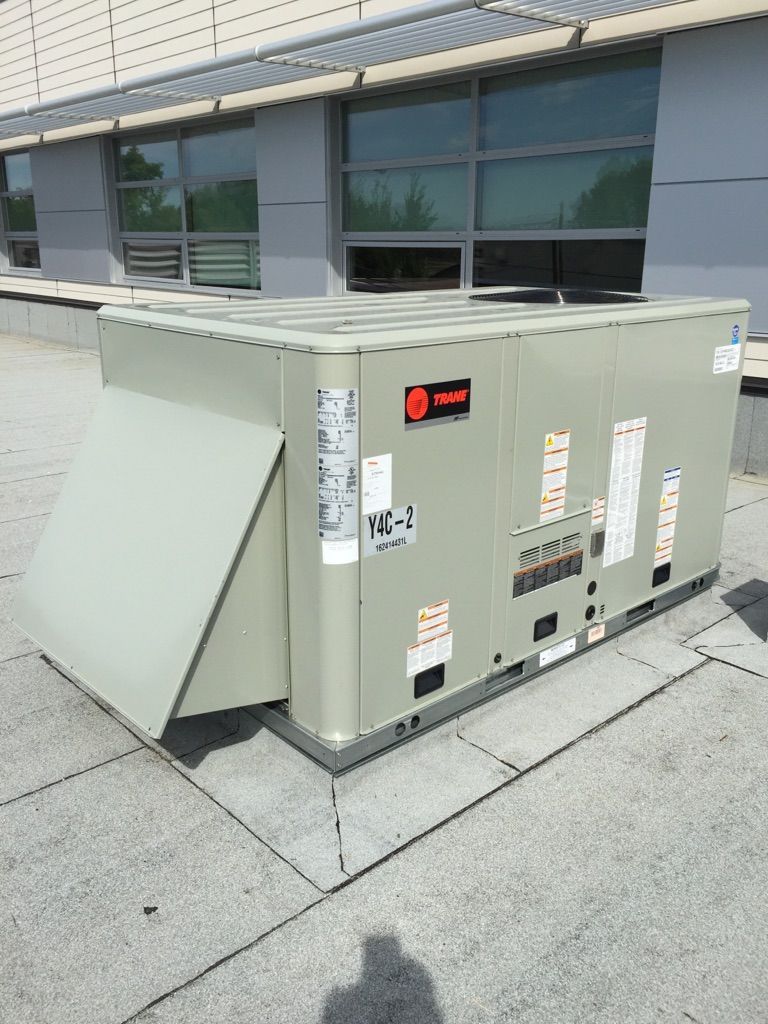 A large air conditioner is sitting on the roof of a building.