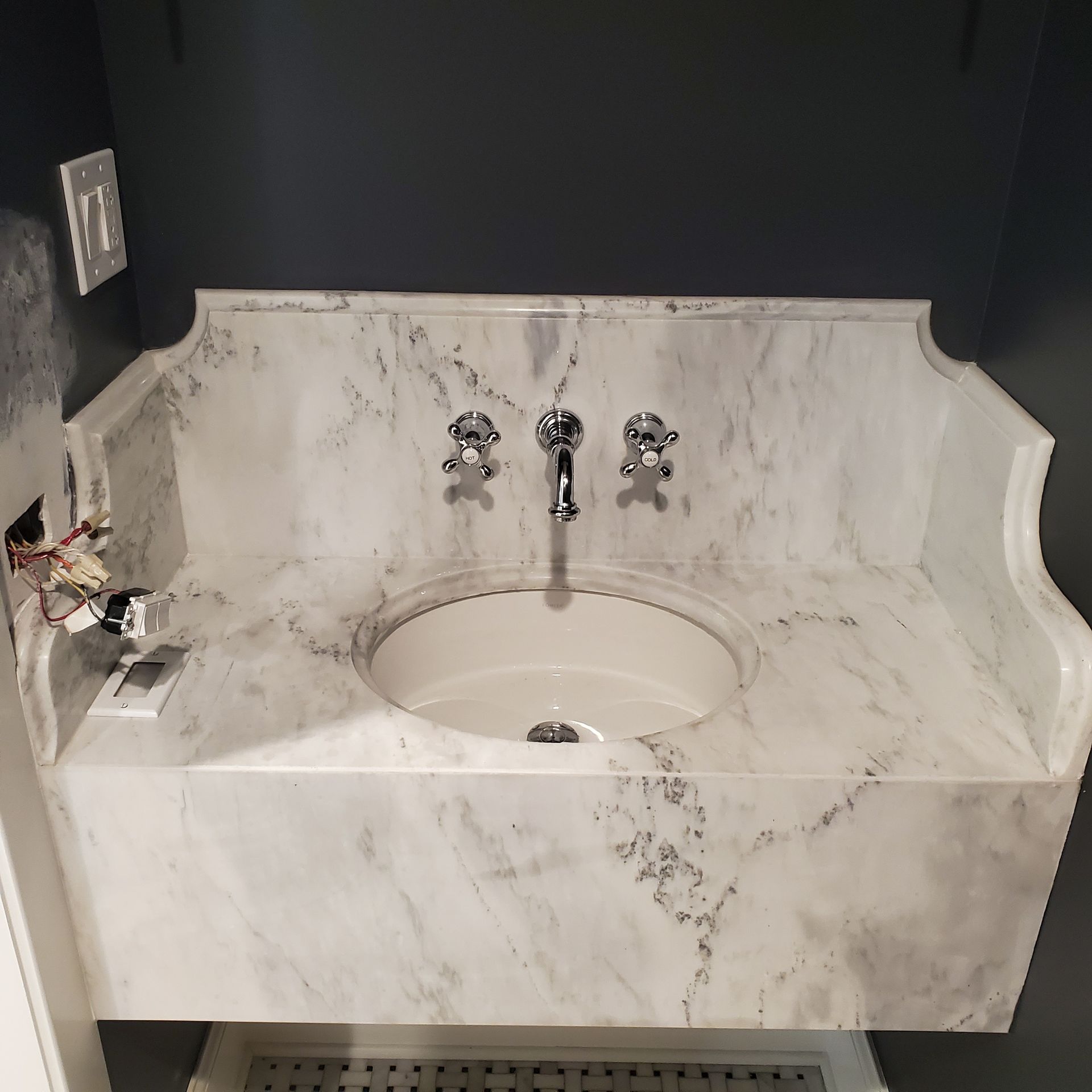 A bathroom sink with a marble counter top and chrome faucets