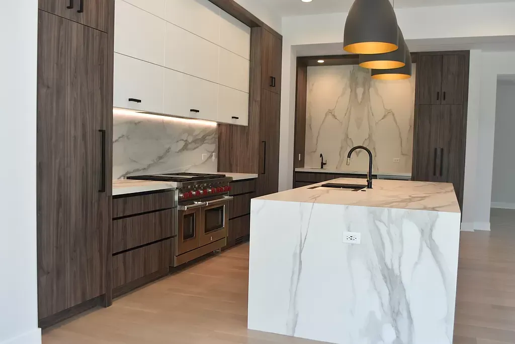 A kitchen with marble counter tops , wooden cabinets , and a large island.