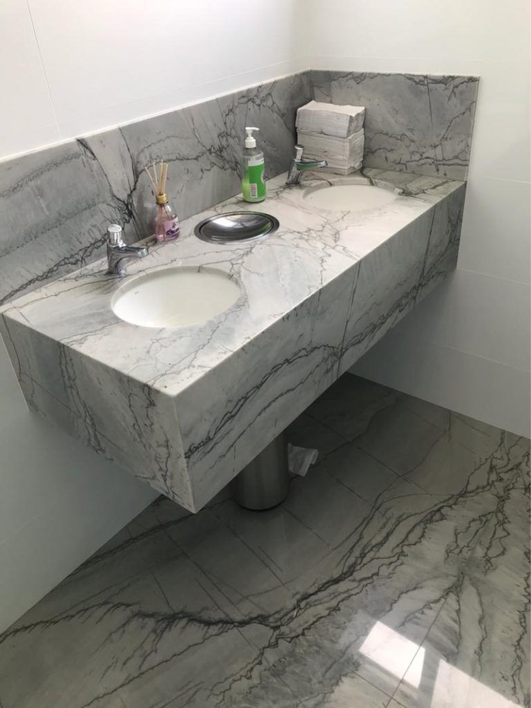 A bathroom with a marble counter top and a sink.