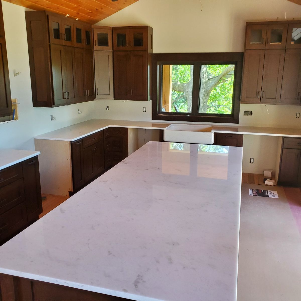 A kitchen with white counter tops and brown cabinets