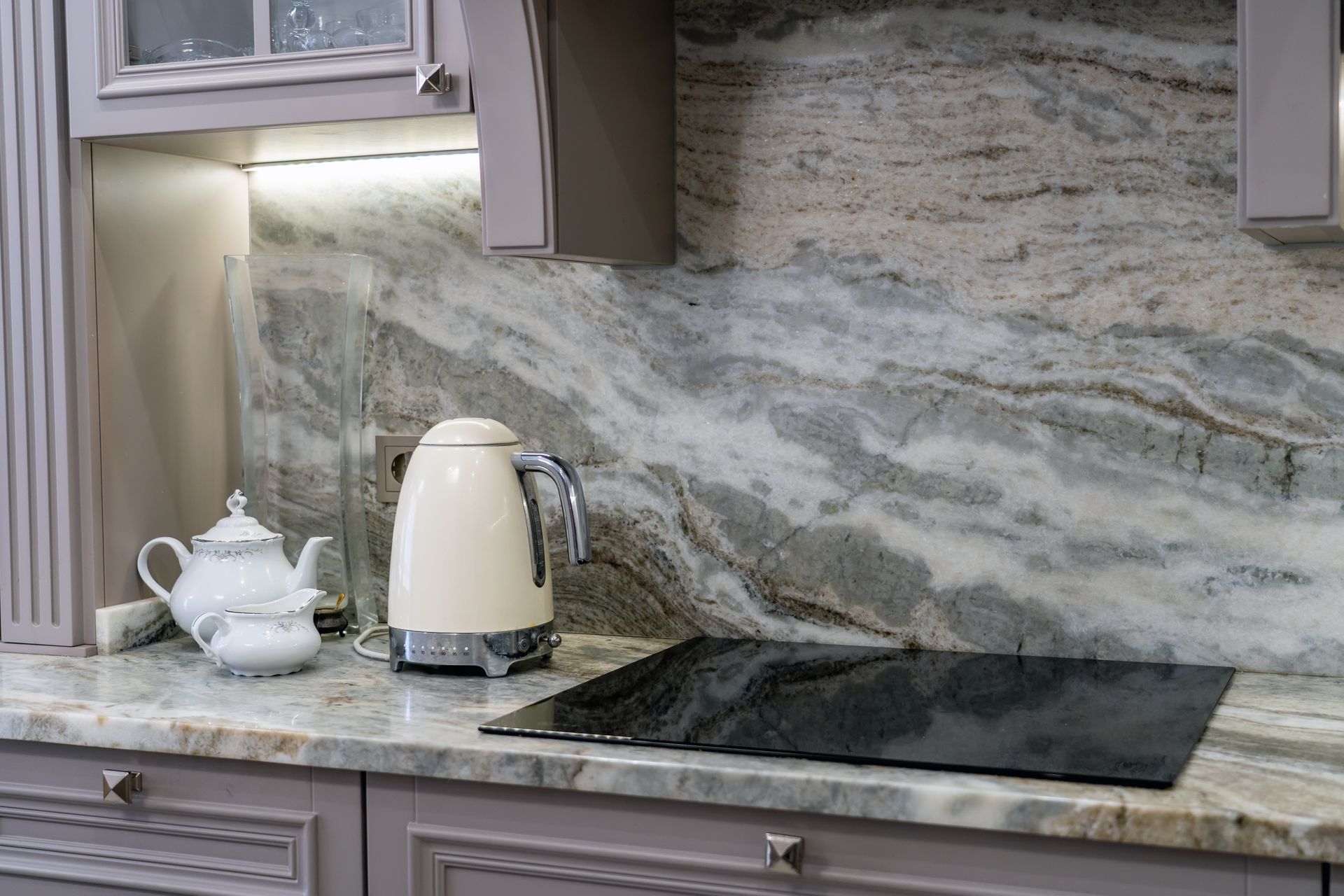A kitchen counter with a kettle and a teapot on it.