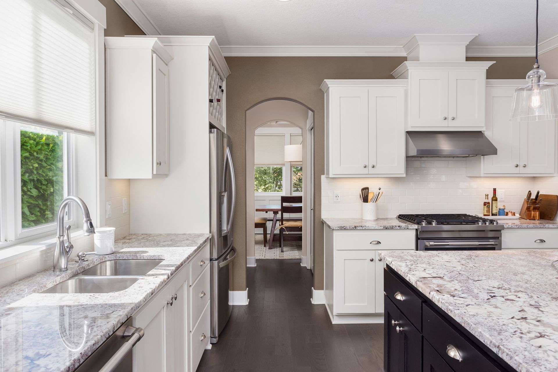 A kitchen with white cabinets and granite counter tops.