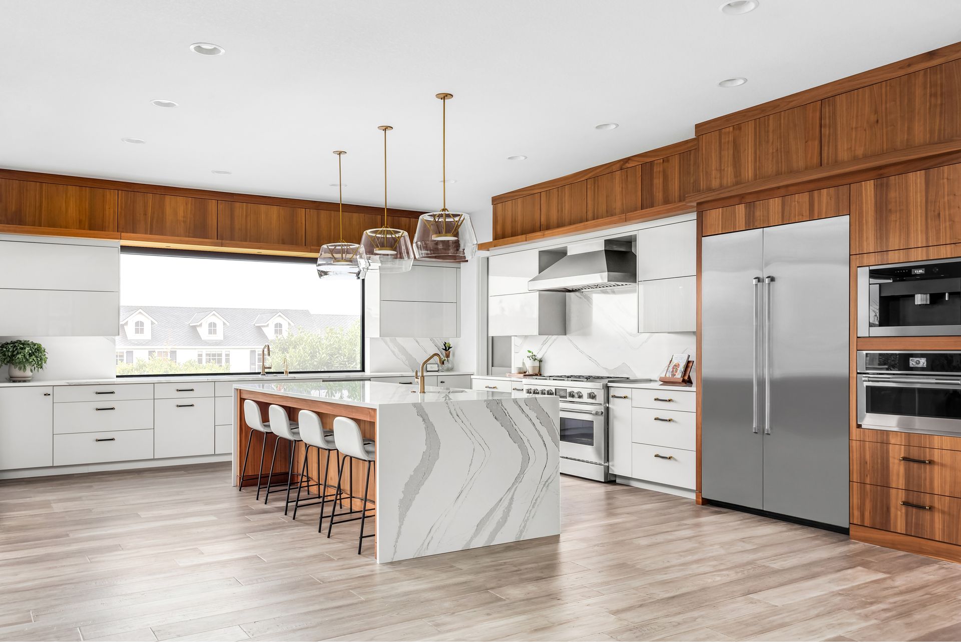 A kitchen with stainless steel appliances , white cabinets , wooden cabinets and a large island.