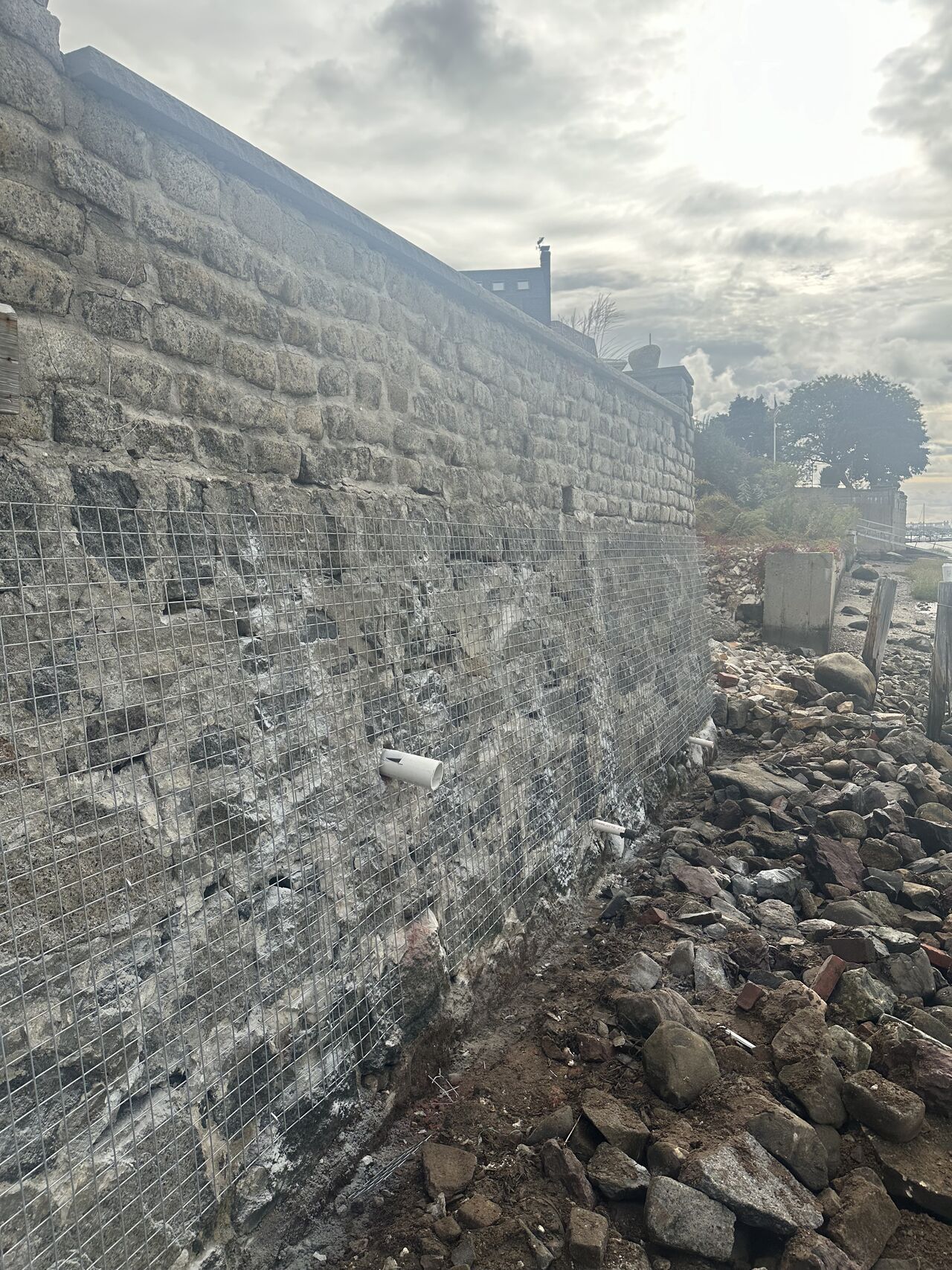 Damaged brick wall and debris. Cloudy sky in the background.