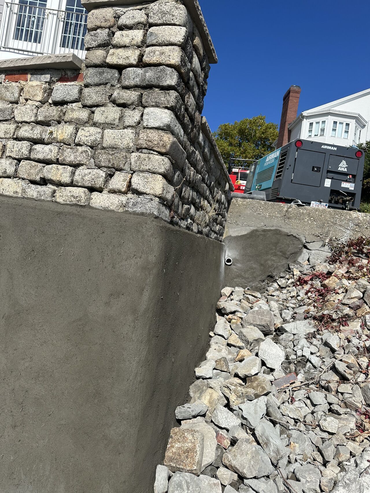 Foundation wall with stone and concrete construction; rubble pile; construction equipment.
