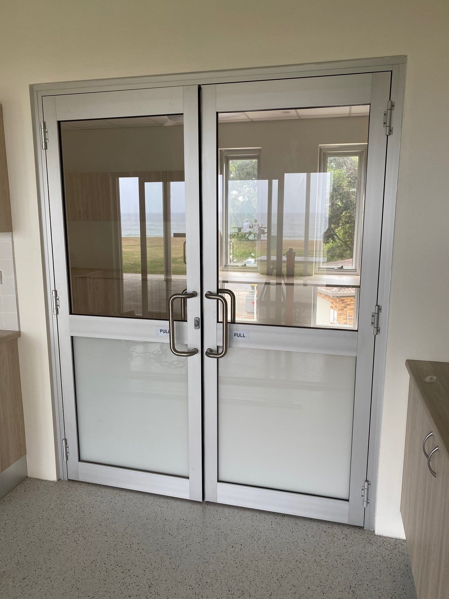 A Pair of Glass Doors in a Room With a View of a Kitchen — Rooney Glass in Coffs Harbour, NSW