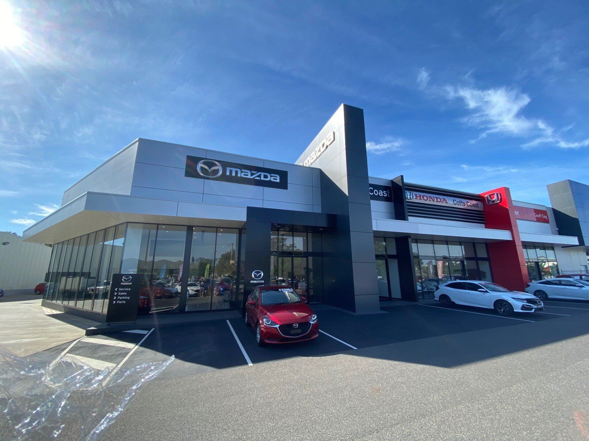 A Red Car is Parked in Front of a Mazda Car Dealership — Rooney Glass in Coffs Harbour, NSW