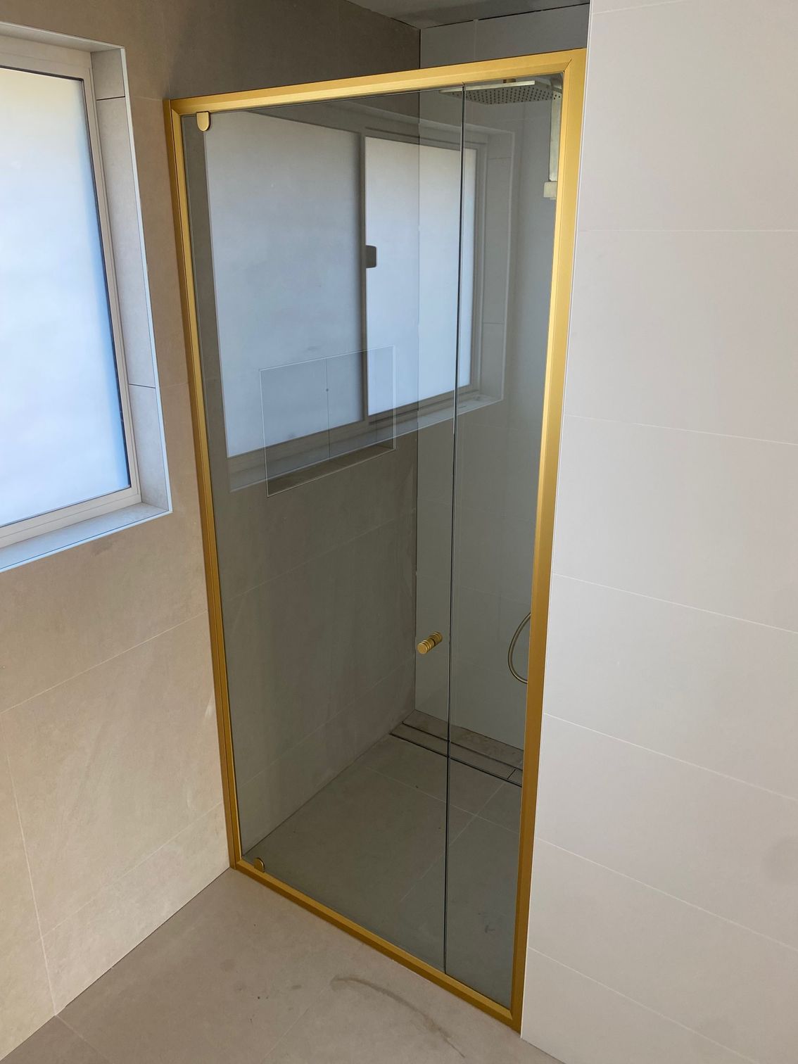 A Bathroom With a Glass Shower Door and a Window — Rooney Glass in Coffs Harbour, NSW