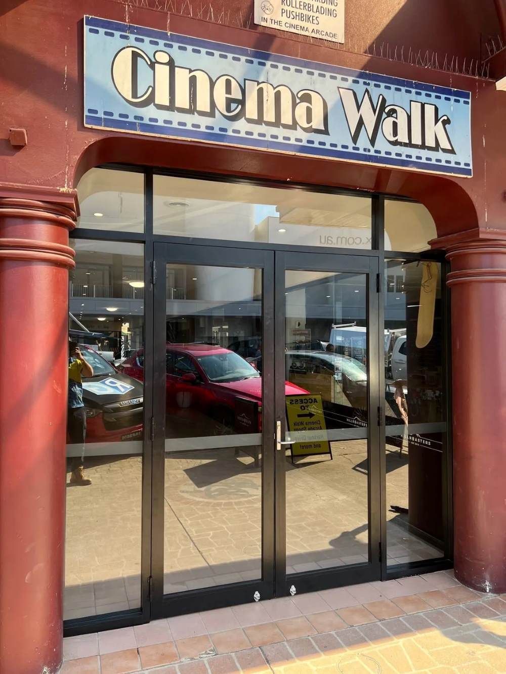 A Red Building With a Sign That Says Cinema Walk — Rooney Glass in Woolgoolga, NSW