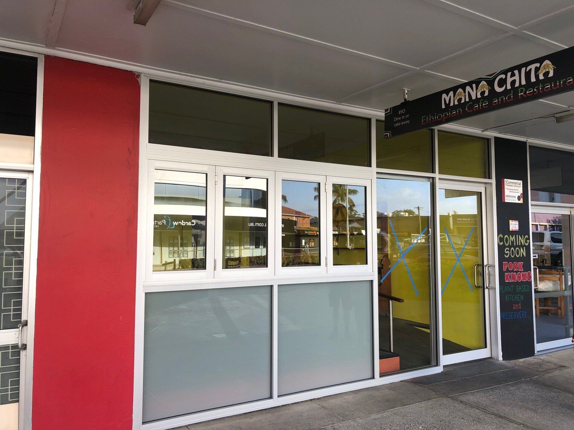 A Building With a Lot of Windows and a Sign That Says Mana Chicken — Rooney Glass in Coffs Harbour, NSW